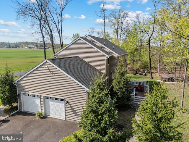 view of property exterior with a lawn, aphalt driveway, and a wooden deck