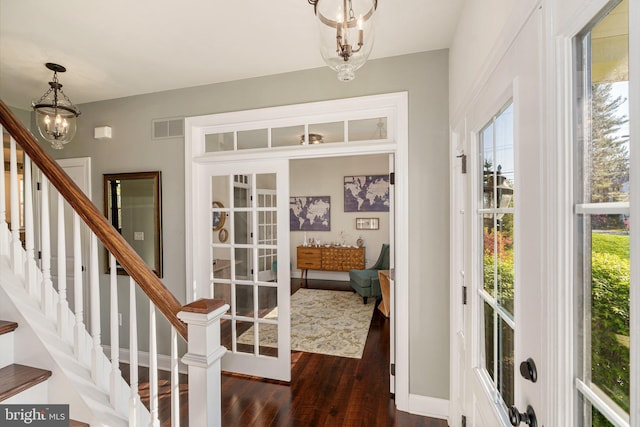 doorway with plenty of natural light, visible vents, stairway, an inviting chandelier, and dark wood-type flooring