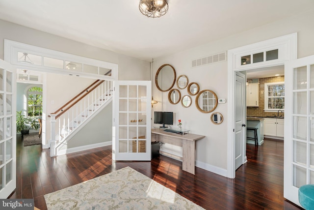 interior space featuring french doors, hardwood / wood-style floors, baseboards, visible vents, and stairway