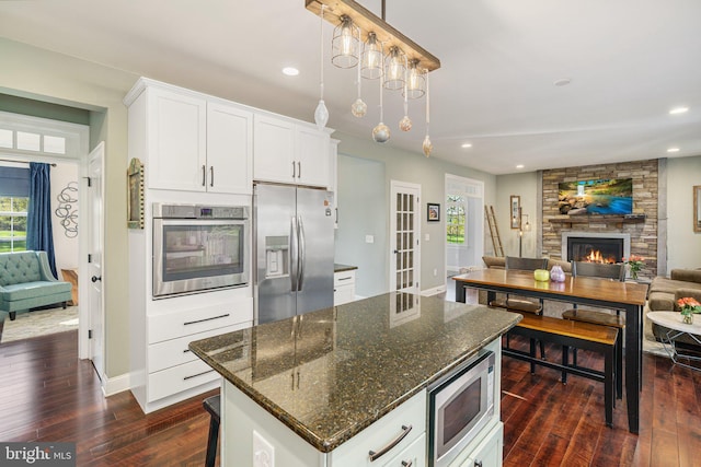 kitchen featuring baseboards, open floor plan, dark wood-style flooring, and stainless steel appliances
