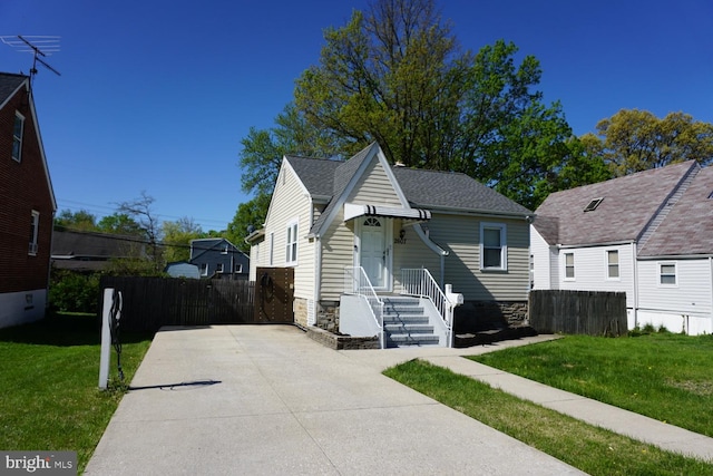 bungalow with fence, a front lawn, driveway, and roof with shingles