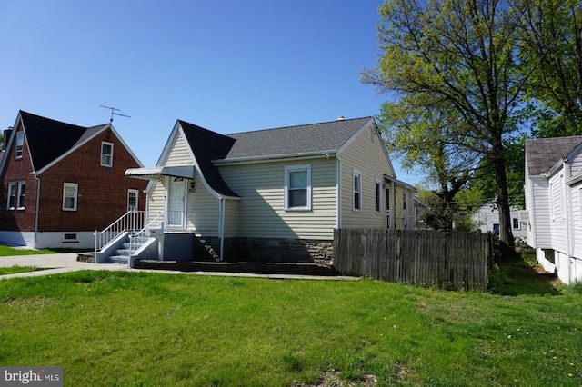back of property featuring a lawn and fence