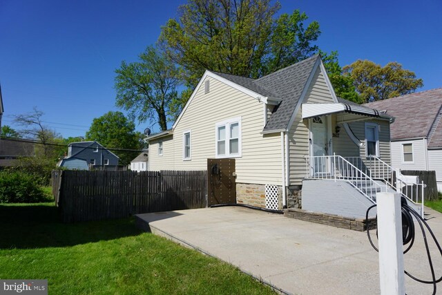 exterior space featuring a lawn, fence, a patio area, and roof with shingles