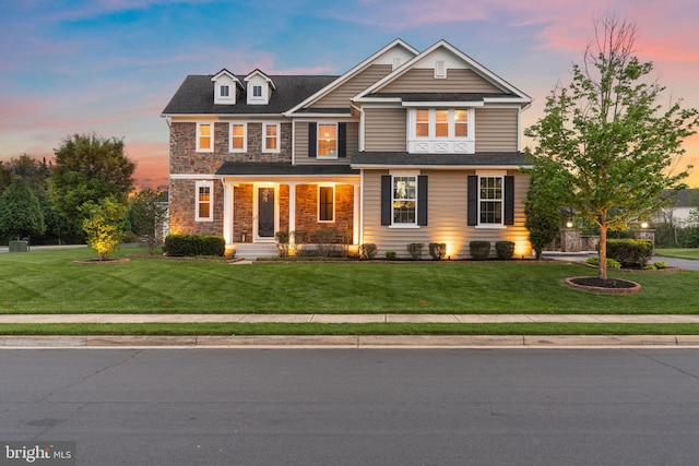 craftsman-style house featuring a porch, a yard, and stone siding