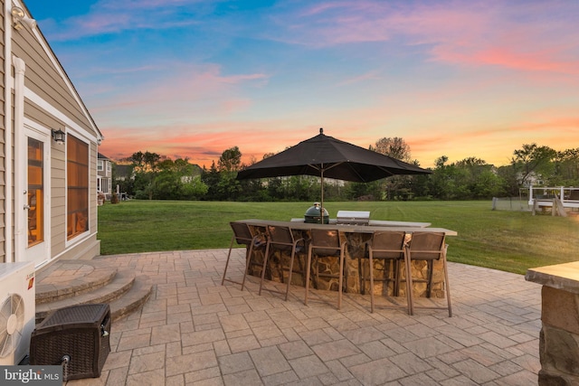 patio terrace at dusk featuring a lawn, outdoor dry bar, and ac unit