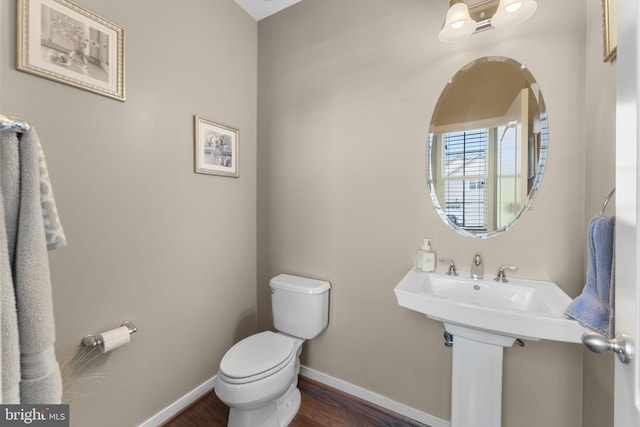 bathroom featuring baseboards, wood finished floors, and toilet