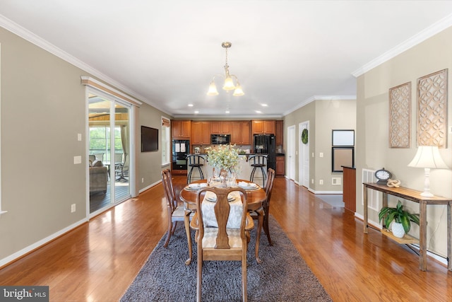 dining room featuring crown molding, baseboards, wood finished floors, and an inviting chandelier