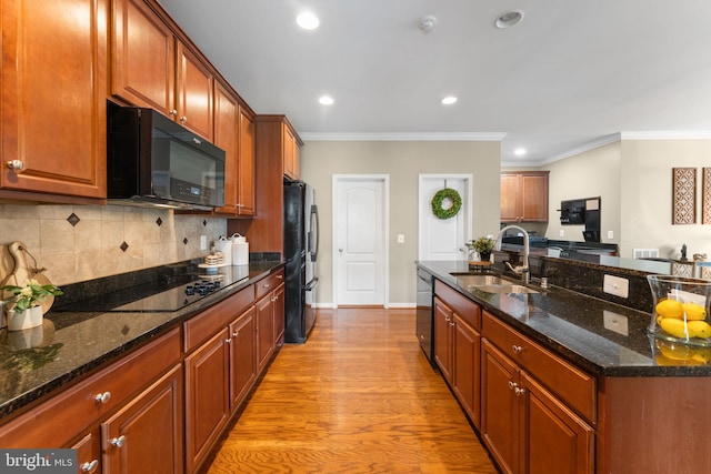 kitchen with a sink, an island with sink, recessed lighting, backsplash, and black appliances