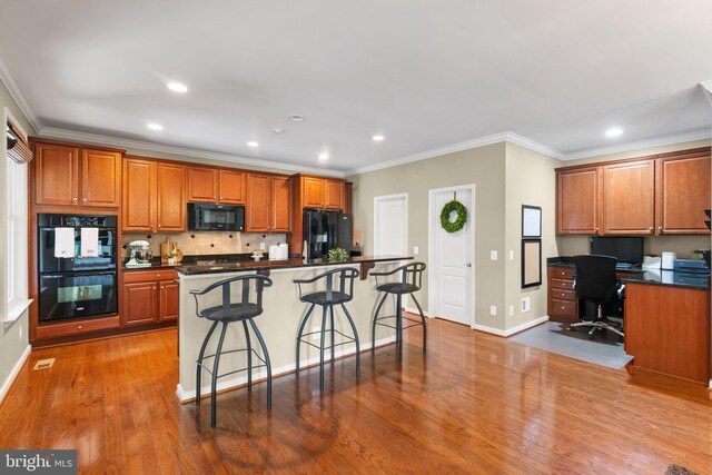 kitchen with decorative backsplash, crown molding, dark countertops, brown cabinets, and black appliances