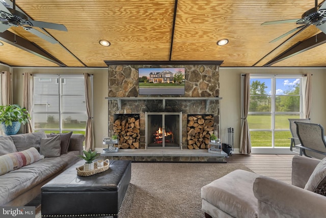 living room with a ceiling fan, a fireplace, and wooden ceiling