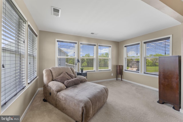 living area with light colored carpet, baseboards, and visible vents