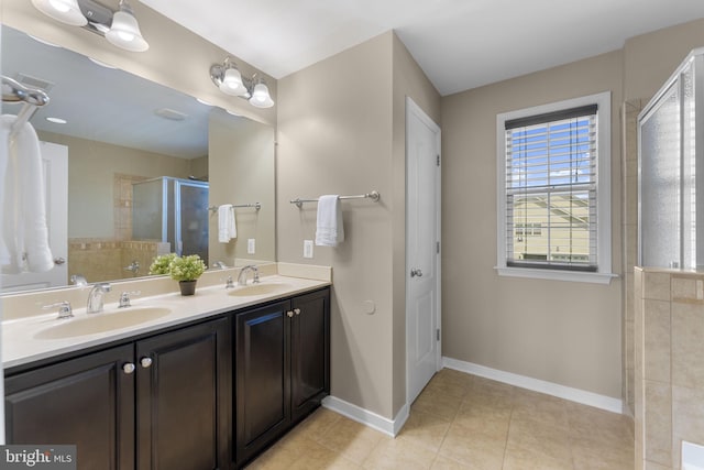 full bathroom with double vanity, a sink, a stall shower, and tile patterned flooring