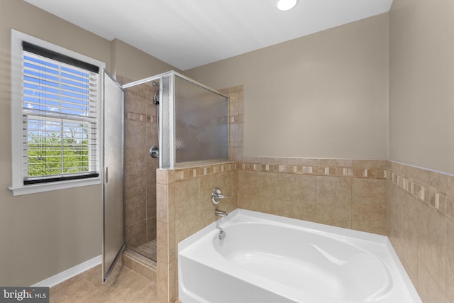 full bathroom featuring a garden tub, baseboards, tile patterned flooring, and a shower stall