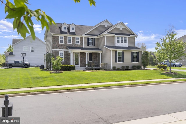 craftsman-style house featuring central AC unit, a front lawn, and stone siding