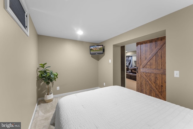 carpeted bedroom featuring baseboards and a barn door