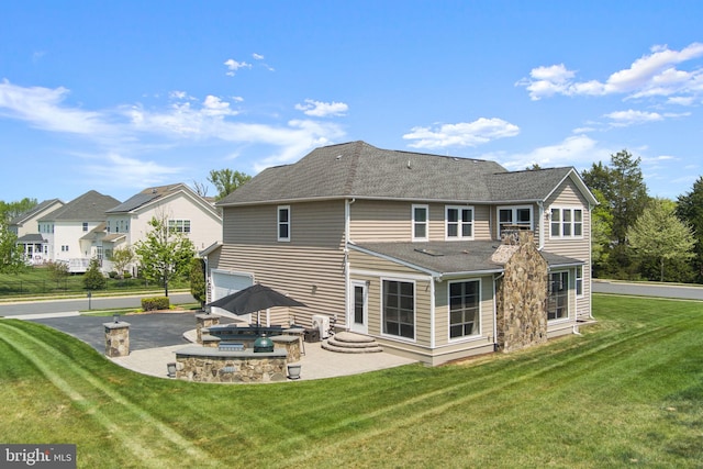 back of property with a patio area, aphalt driveway, a yard, an attached garage, and a shingled roof