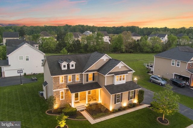 view of front of property featuring a yard, a porch, driveway, and stone siding