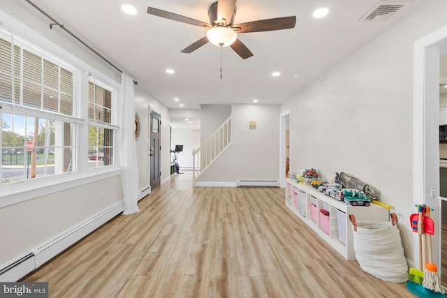 recreation room with light wood-style floors, baseboard heating, a baseboard heating unit, and visible vents
