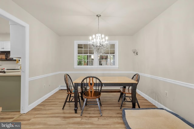 dining area featuring baseboards, light wood-style flooring, a baseboard heating unit, and a notable chandelier