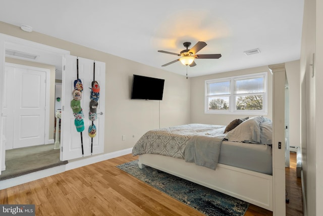 bedroom with visible vents, baseboards, ceiling fan, and wood finished floors