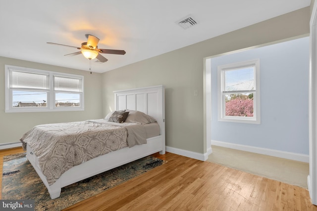 bedroom with multiple windows, light wood-style flooring, and visible vents