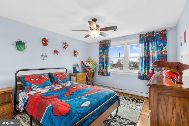 bedroom with wood finished floors, ceiling fan, and a baseboard heating unit