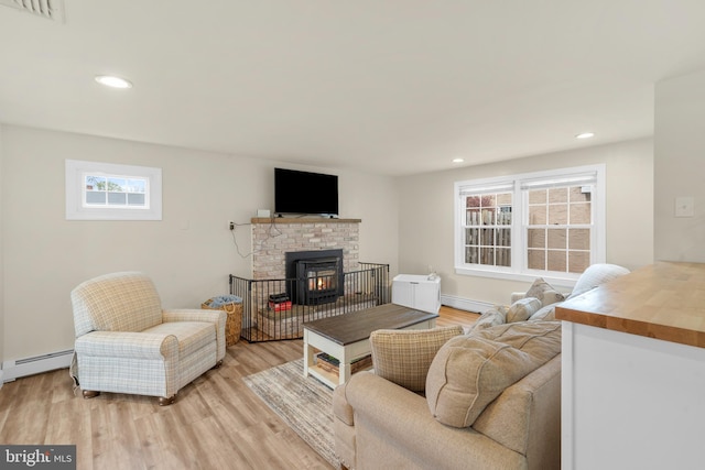 living room with a wealth of natural light, light wood-style flooring, and a baseboard radiator