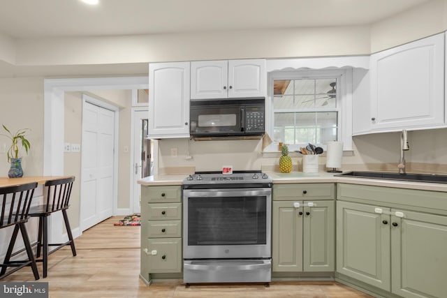 kitchen with electric range, black microwave, white cabinetry, and a sink