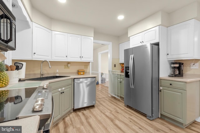 kitchen with a sink, white cabinets, stainless steel appliances, recessed lighting, and light wood-style flooring