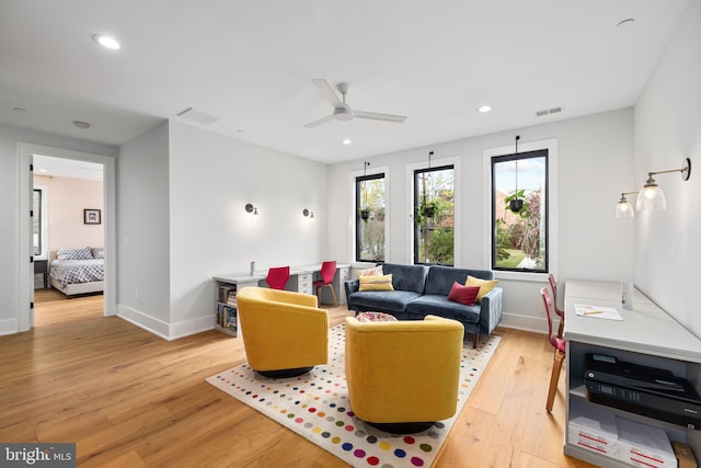 living room featuring visible vents, a ceiling fan, baseboards, and light wood-style floors