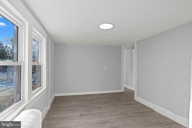 spare room featuring baseboards, a healthy amount of sunlight, and wood finished floors