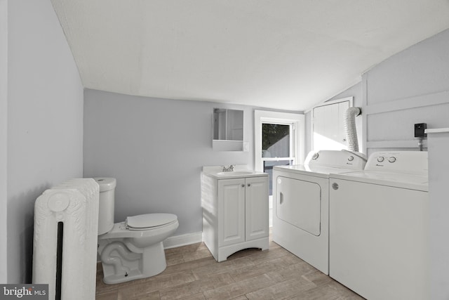 bathroom featuring toilet, wood finished floors, washer and dryer, radiator, and lofted ceiling