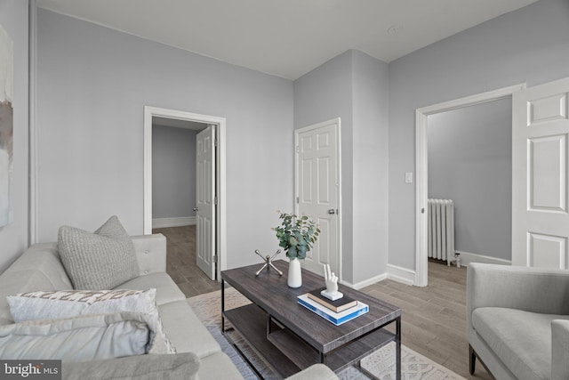 living room with radiator, baseboards, and light wood finished floors