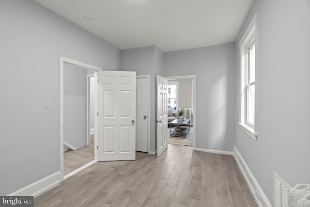 unfurnished bedroom with baseboards, light wood-style flooring, and visible vents