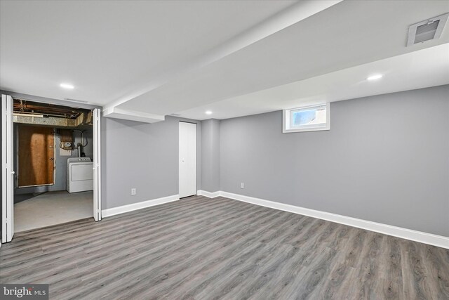 below grade area with visible vents, wood finished floors, baseboards, washer / dryer, and recessed lighting
