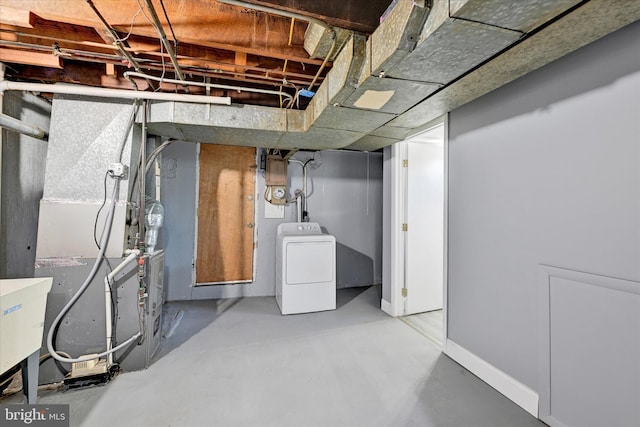 unfinished basement featuring baseboards and washer / dryer