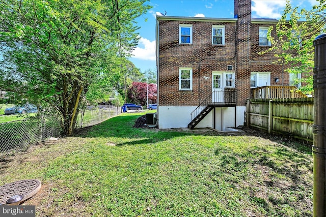 rear view of property with brick siding, a fenced backyard, a lawn, and central AC