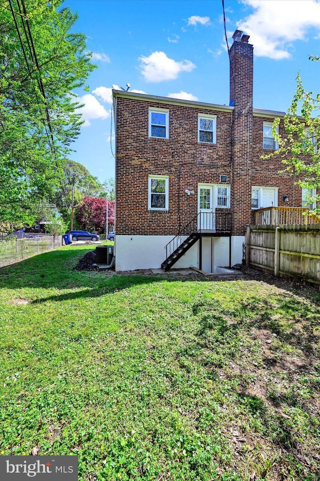 back of house with a yard, fence, a chimney, and central AC unit