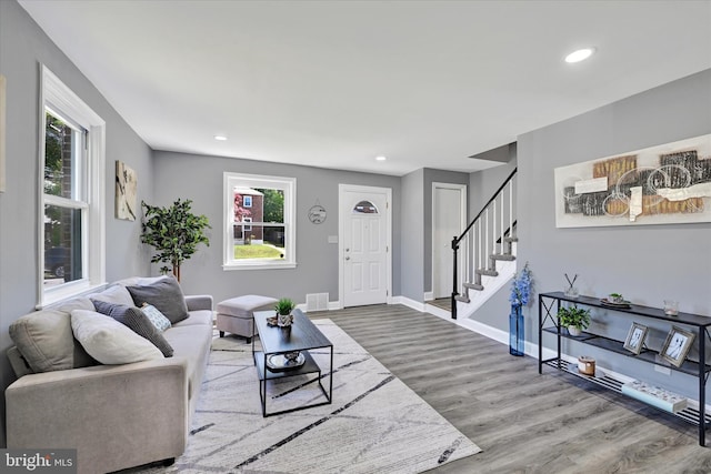 living area with stairway, recessed lighting, wood finished floors, and a wealth of natural light