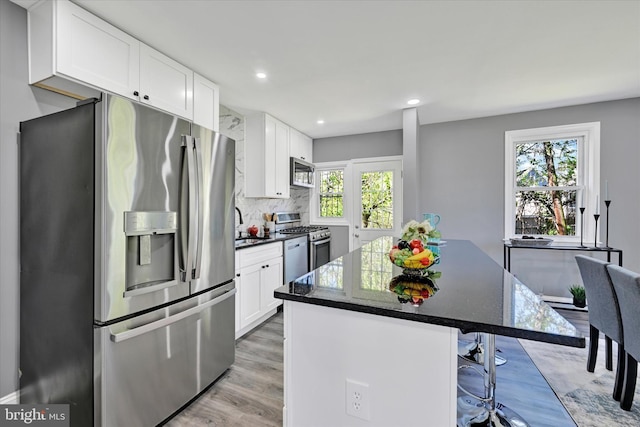 kitchen with a center island, light wood-style floors, a breakfast bar, stainless steel appliances, and white cabinetry