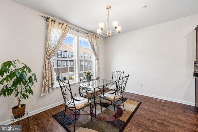 dining room featuring baseboards, a chandelier, wood finished floors, and visible vents
