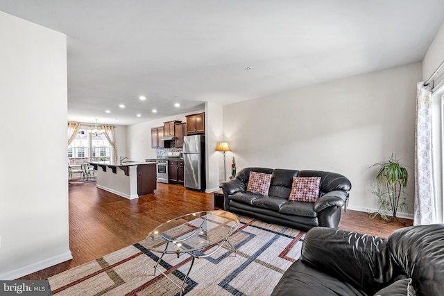 living room with baseboards, recessed lighting, dark wood-style floors, and an inviting chandelier