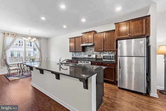 kitchen featuring dark wood-style flooring, baseboards, a sink, a notable chandelier, and stainless steel appliances