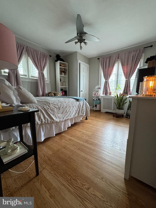 bedroom with radiator heating unit, wood finished floors, and ceiling fan