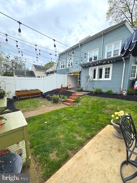 rear view of house with fence and a lawn