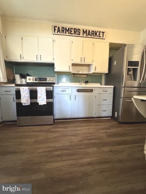 kitchen featuring dark wood-style flooring, light countertops, ornamental molding, white cabinets, and appliances with stainless steel finishes