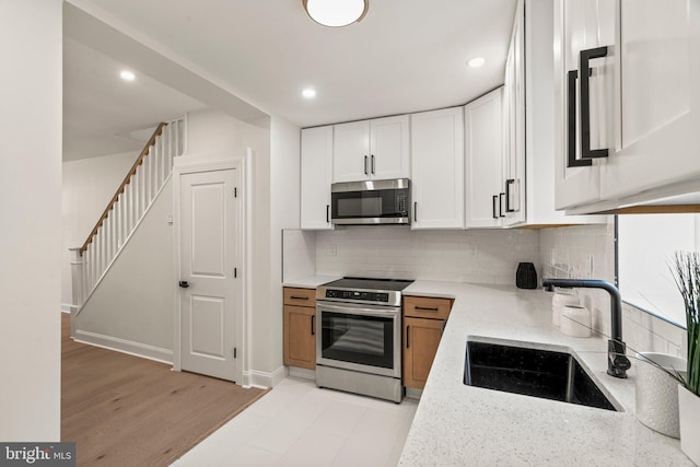 1102 Mercy St, Philadelphia, PA 19148 - kitchen featuring light stone counters, a sink, white cabinets, backsplash, and appliances with stainless steel finishes