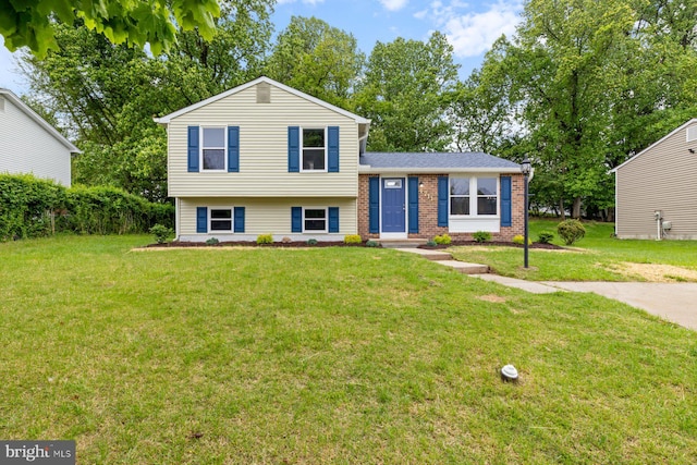 split level home featuring a front lawn and brick siding