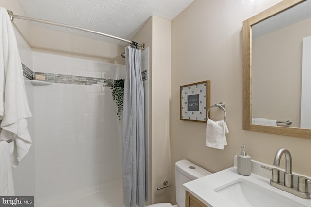 full bathroom with toilet, vanity, a tile shower, and a textured ceiling