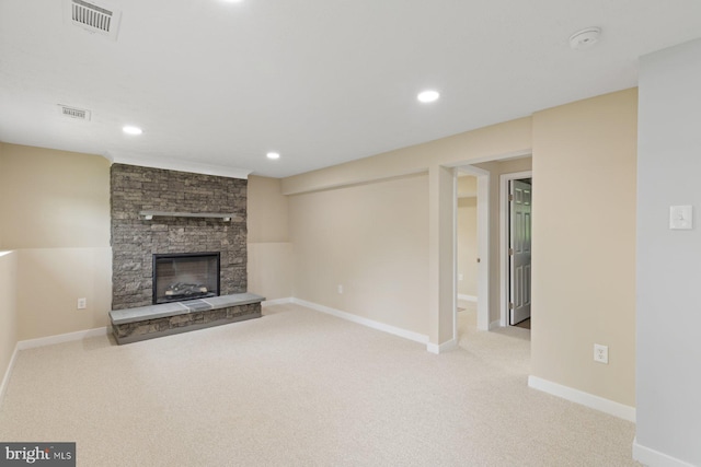 unfurnished living room with carpet, a stone fireplace, baseboards, and recessed lighting